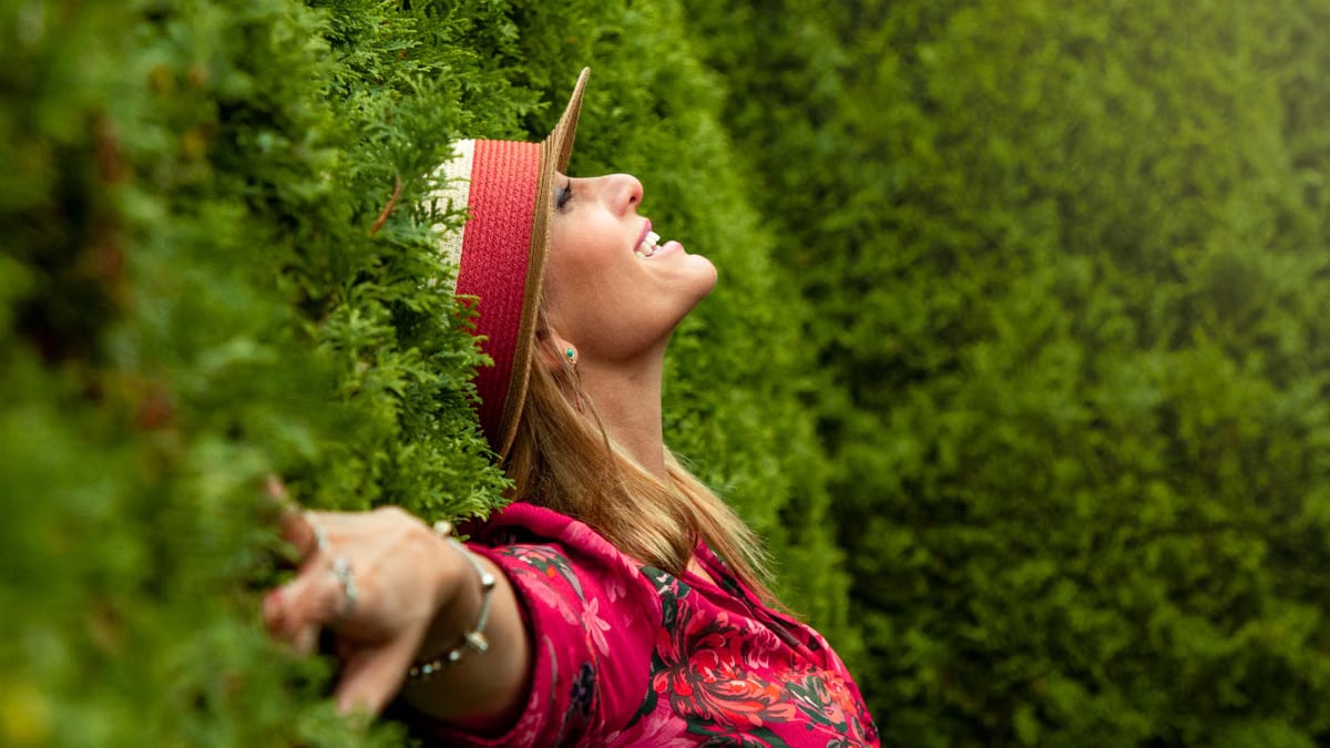 A joyful woman enjoying nature, embracing freedom in a lush green park.